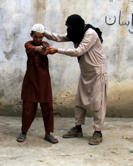 Am Islamic State militant shows a child how to use a gun in Kunar province, Afghanistan.