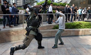 A riot police officer clashes with a protester in Hong Kong’s central district as workers look on.