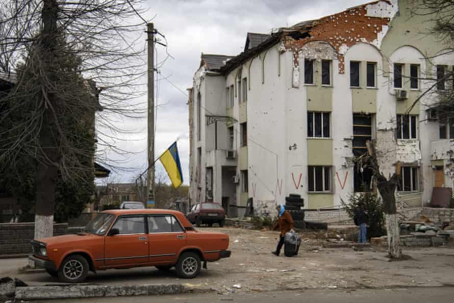 A local woman carries belongings from a damaged house in the town of Borodianka, northwest of Kyiv.