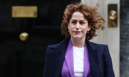 Victoria Atkins departs 10 Downing Street: she has red hair which is blowing in the wind, and is wearing a dark blue coat, mauve jacket and white top, with red lipstick