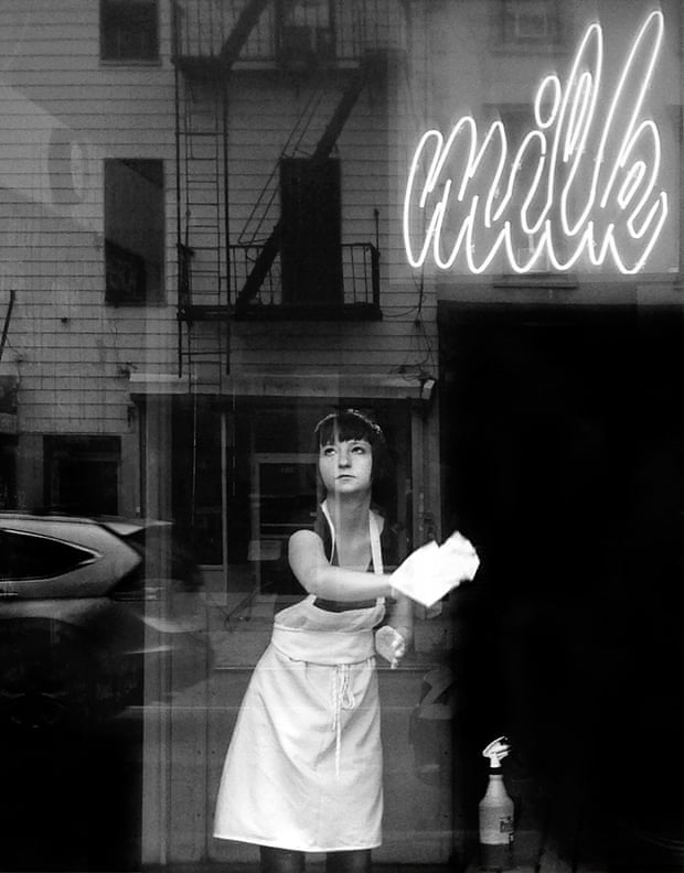 Black and white shot of a deli worker in New York wiping a window and gazing out