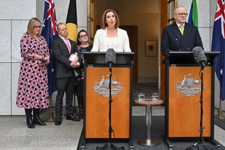 Parents Mia Bannister, Robb Evans and Emma Mason watch Anika Wells and Anthony Albanese at a press conference