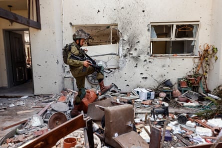 An Israeli soldier steps over personal belongings near a home in in kibbutz Beeri following the attack by Hamas gunmen.