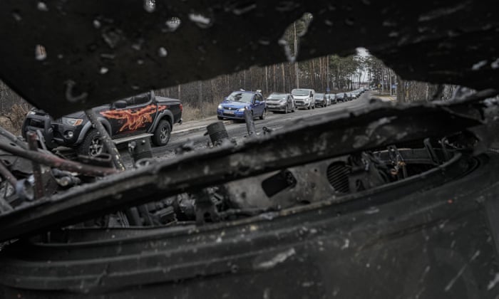 Cars drive past a destroyed Russian tank as a convoy of vehicles evacuating civilians leaves Irpin, on the outskirts of Kyiv, Ukraine.
