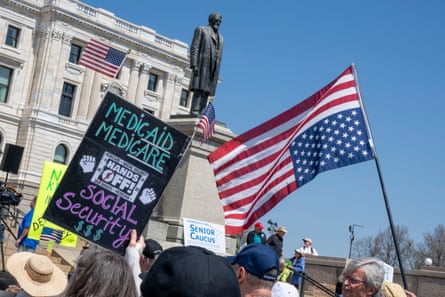 People holding posters and an upside-down US flag.