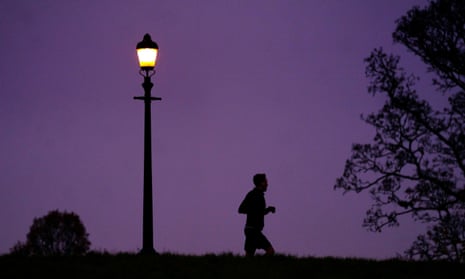 Person jogging at night beside street lamp