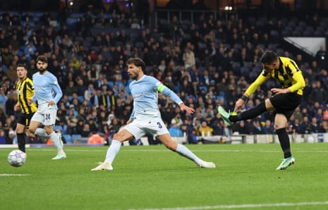 AEK Athens' Stavros Pilios strikes the ball to score as a Manchester City defender lunges