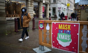 Christmas shoppers walk a past a sign saying 'Mask Up For Christmas’ in Manchester, UK.