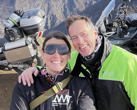 Craig and Lindsay Foreman in biking clothes, motorbikes and mountains behind