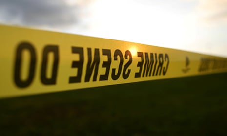 Yellow crime scene tape is seen in front of a setting sun.