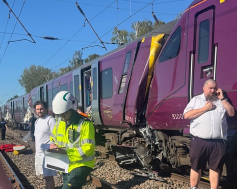 Emergency responders in high-visibility jackets attend to two damaged trains with crumpled front end on railway tracks