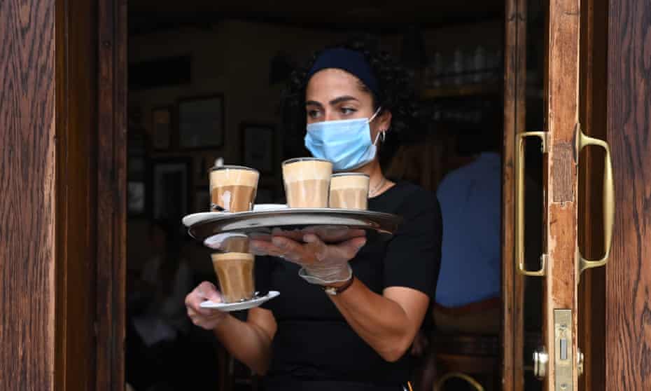 A waitress serves coffees in a bar in Soho, central London, July 2020.