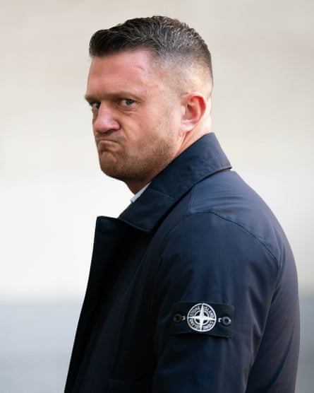 Portrait of Tommy Robinson in dark blue Stone Island jacket seemingly snarling at the photographer.