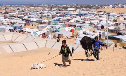 Children walk with a dog near the tents of displaced Palestinians in Rafah.