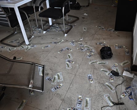 Fake dollar bills on the floor along side chairs that have fallen over.