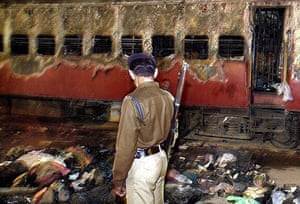 A police officer examines a charred train and the belongings of Hindu activists at Godhra railway station on 28 February 2002. A Muslim crowd set alight the train, killing at least 57 people including 15 children, as they returned from the disputed Babri mosque