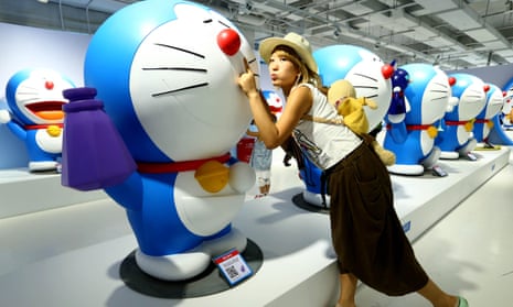 A girl poses for photos with figures of Doraemon