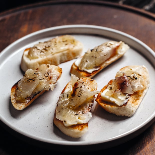 Five portions of cured sea bass on a slice of baguette on a plate