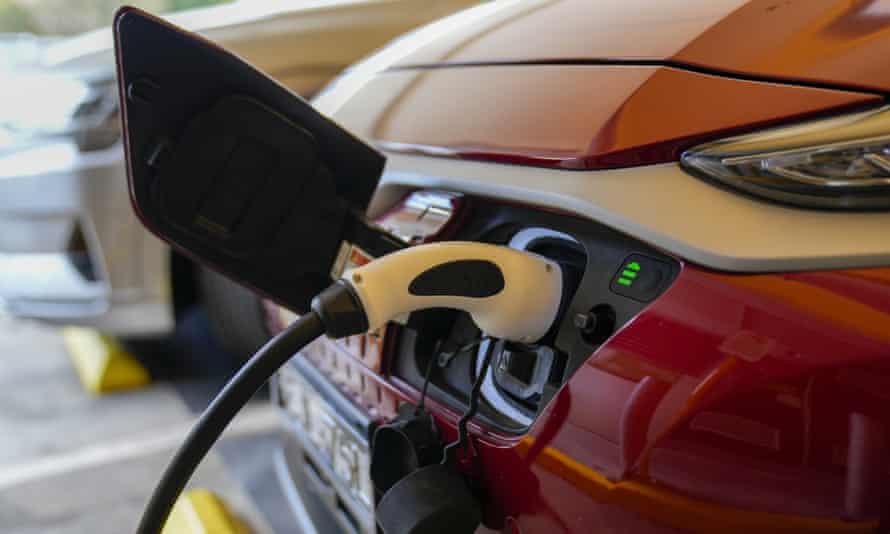 An electric car gets charged at a supermarket car park