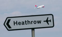 a road sign saying Heathrow with a jet taking off in the background