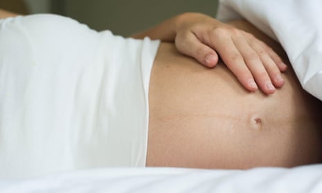 Pregnant woman lying in bed with hand on stomach