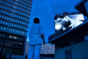 A man watches a slide show of Muhammad Ali photos displayed on a screen on Thursday, outside the KFC Yum! Center, where mourners will attend a memorial service for the boxing legend