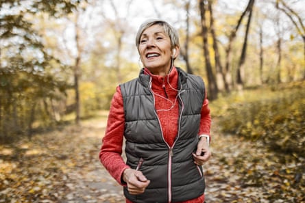 a senior woman jogging on a forest road