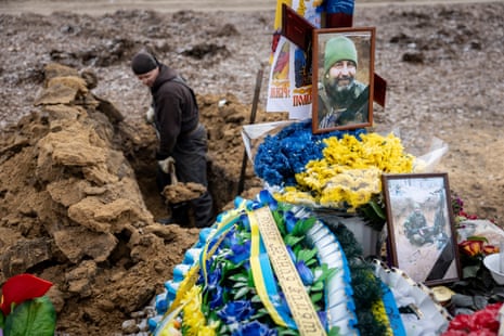 A grave digger digs a new hole within the military section of a cemetery in Kharkiv, Ukraine.