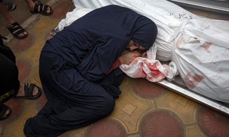 A woman mourns next to the bodies of her child and her husband.