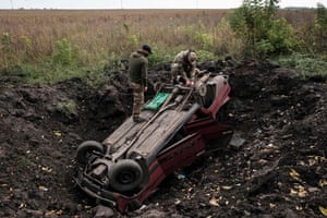 Ukrainian soldiers scavenge from a destroyed car near Prudyanka, Ukraine