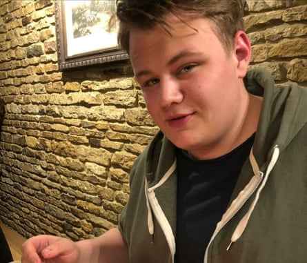 he has fair hair and wears a khaki green hooded sweatshirt