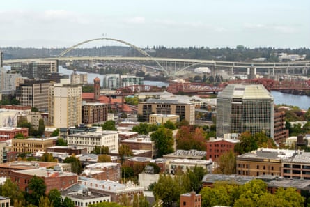 An aerial view of a city on a river, with a curved bridge in the background.