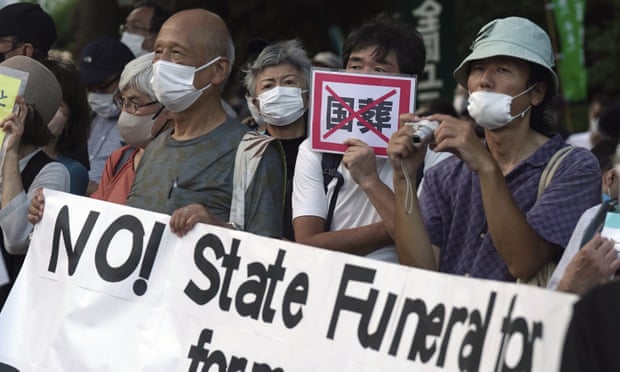 Protesters on Wednesday hold signs against a state funeral for former prime minister Shinzo Abe.