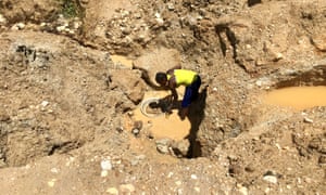 A woman digs for gold where locals once dug for crops.