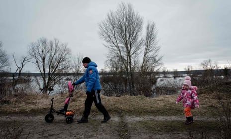 Yury (L) and his daughter Ania, 4, walk on a dyke near the swamp that turned into a lake.