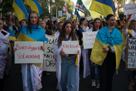 Woman hold placards and Ukrainian flags in Paris.