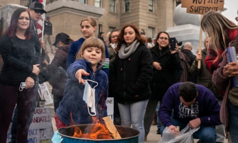 A child tosses a surgical mask into a fire at the Idaho capitol.