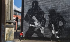 a young boy runs past a loyalist paramilitary mural in Belfast, Northern Ireland. 