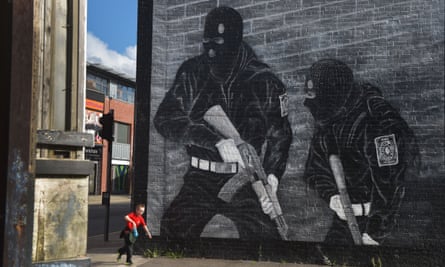 A young boy runs past a loyalist paramilitary muralin Belfast.