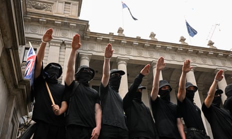 Black-clad and masked men perform the Nazi salute on the steps of Parliament House