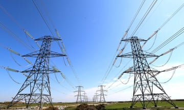 towering electricity pylons stretch across a green field amid a blue sky