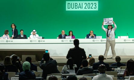 This image grab taken from AFPTV video footage shows an activist protesting on stage against fossil fuels during an event at the United Nations Climate Conference (COP28) in Dubai on December 11, 2023.