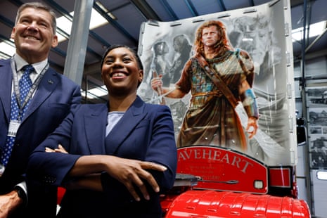 Kemi Badenoch posing in front of a truck with a Braveheart mural.