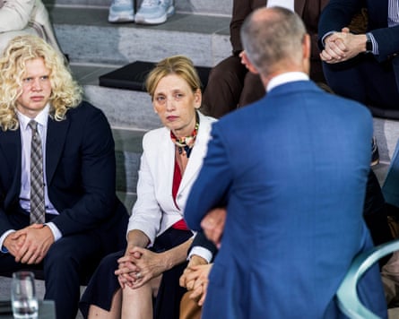 Karin Prien seated on assembly hall benches listening to Friedrich Merz standing in front of her