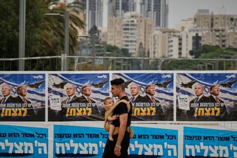 A man walks past a banner featuring images of Netanyahu and Trump
