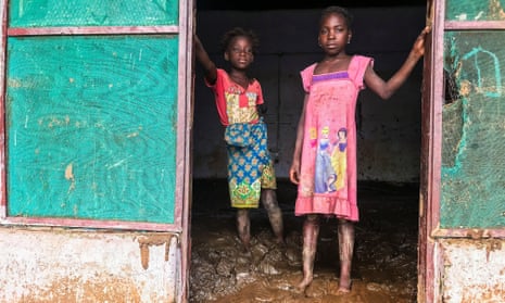Children stand inside their house covered with mud after Storm Ana hit the district of Tete, Mozambique.