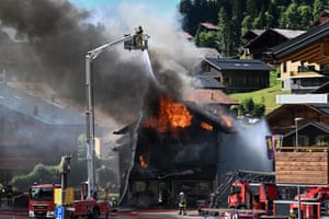 A firefighter at the top of a crane sprays a hose at a burning building