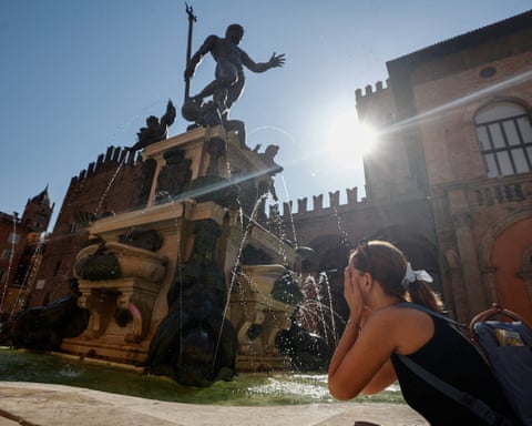 A woman splashes water on her face at the Fountain of Neptune in Bologna, Italy.