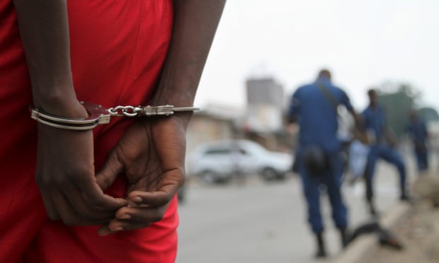 A suspect is handcuffed and detained by policemen in Burundi 
