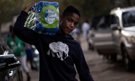 A volunteer carries bottles of water at a water distribution site as the city of Jackson, Mississippi.